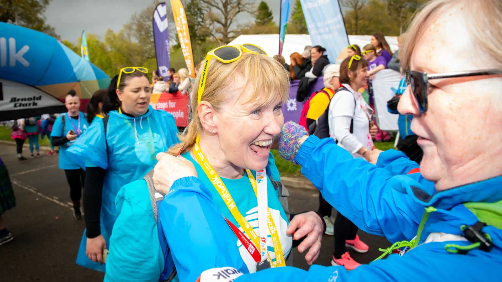 A woman celebrates as she receives her Kiltwalk medal at the finish line.