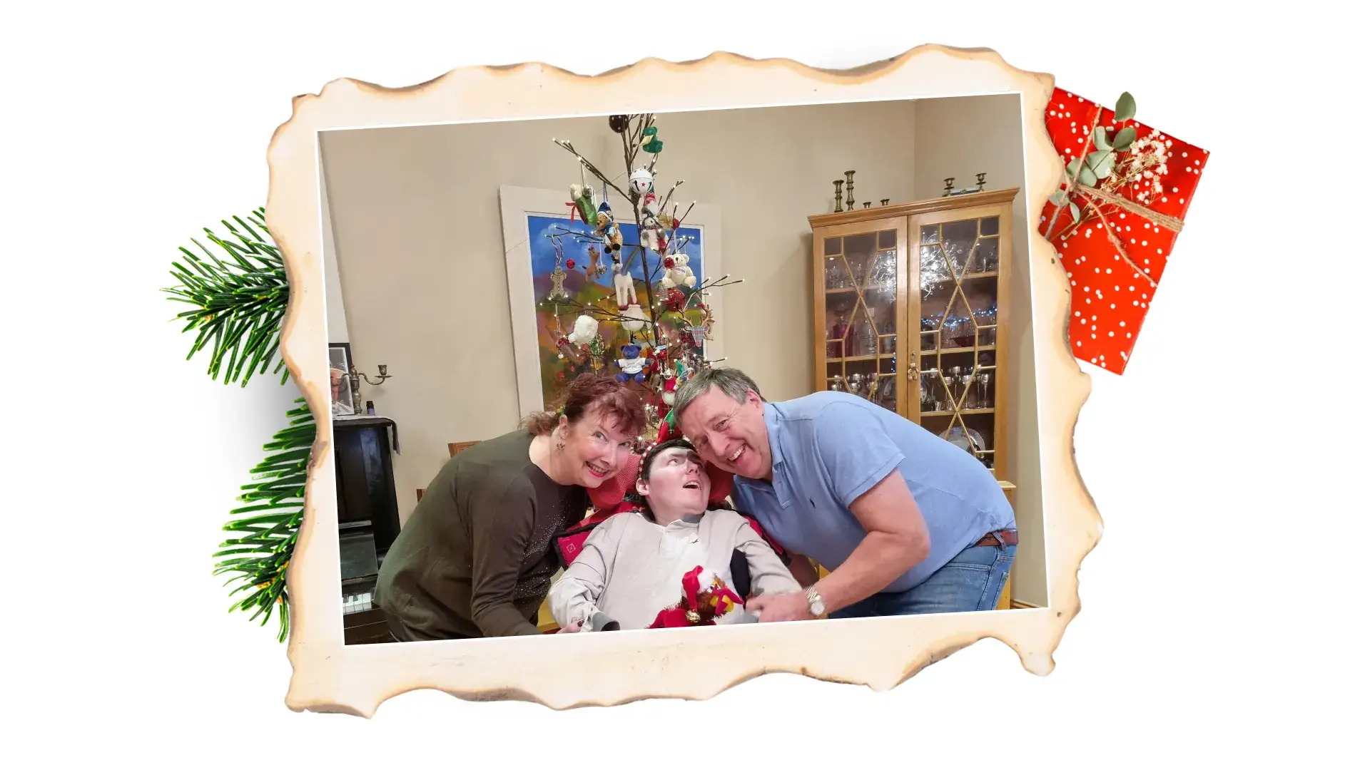 A boy and his parents posing for the camera in front of a Christmas tree