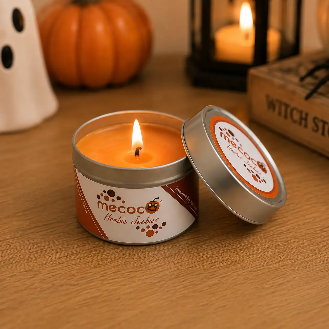 A Mecoco candle with the label 'Heebie Jeebies'. The wax is orange and the wick is burning.