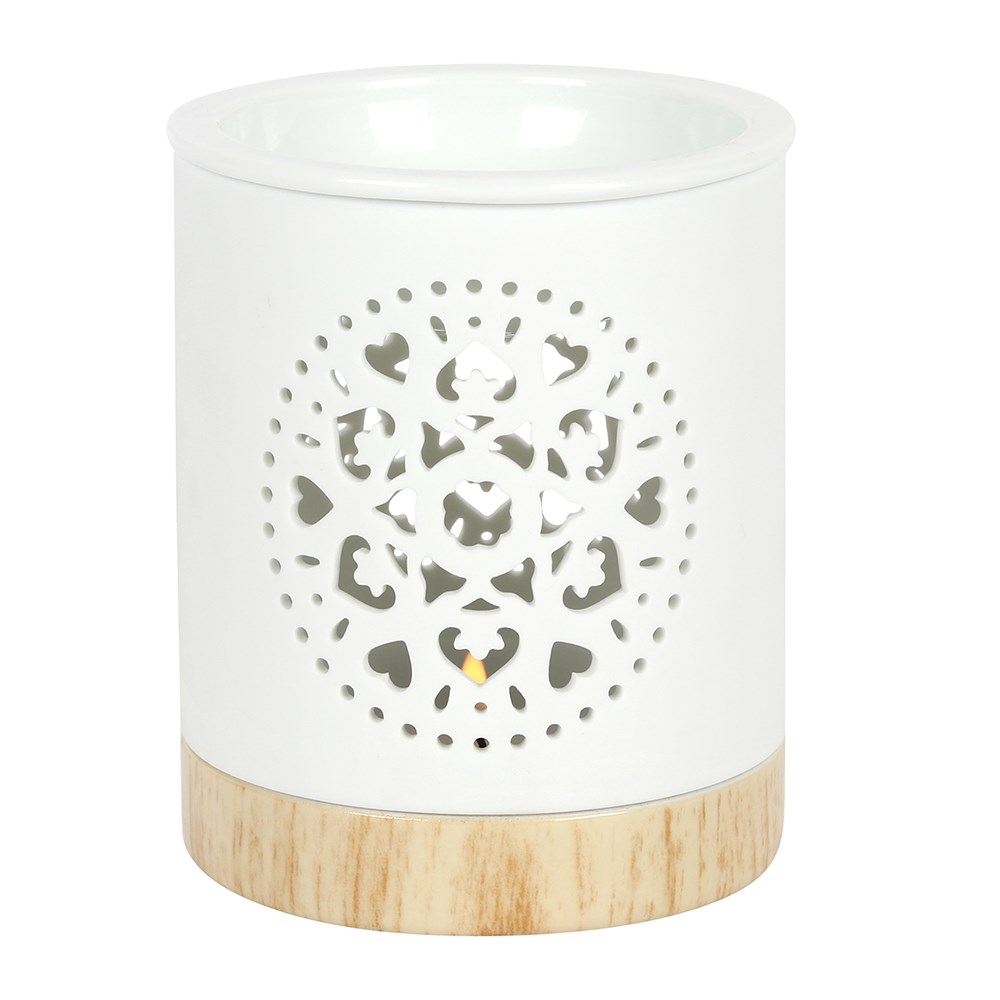 A white wax melt burner with a mandala carved into it. The burner has a wooden base.