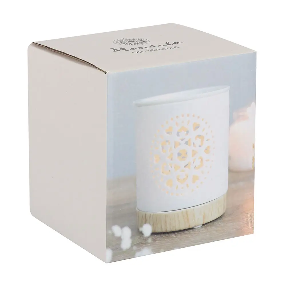 A cardboard box with an image on the front, depicting a white wax melt burner with a mandala carved into it. The burner has a wooden base.