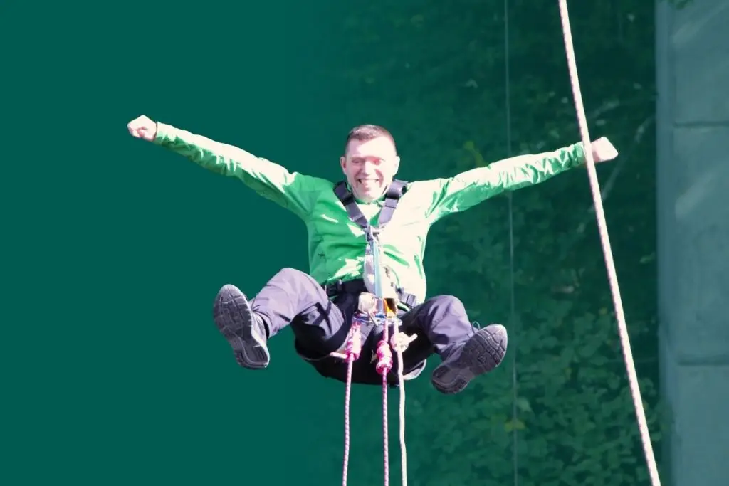 a man grinning in mid-air with his arms outstretched