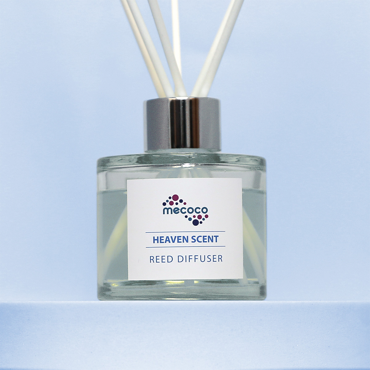 A glass reed diffuser with a sticker featuring the Mecoco logo and text which says 'Heaven Scent Reed Diffuser'.
